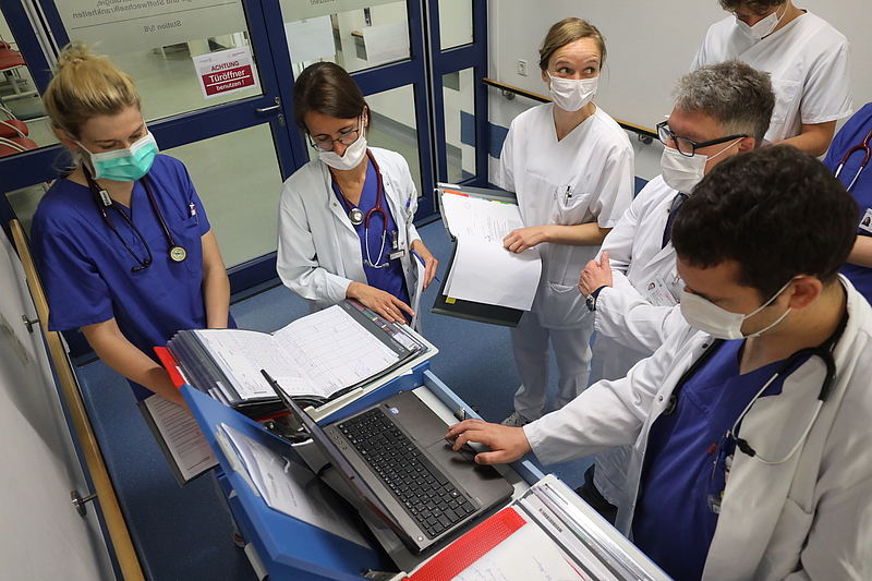 Gruppe von Ärzten steht um einen Laptop